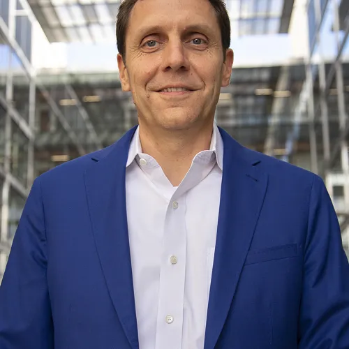 A man in a blue suit standing in front of a building.