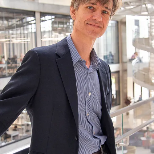 A man in a suit standing on a railing.