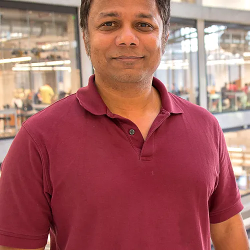 A man in a maroon shirt standing in an office.